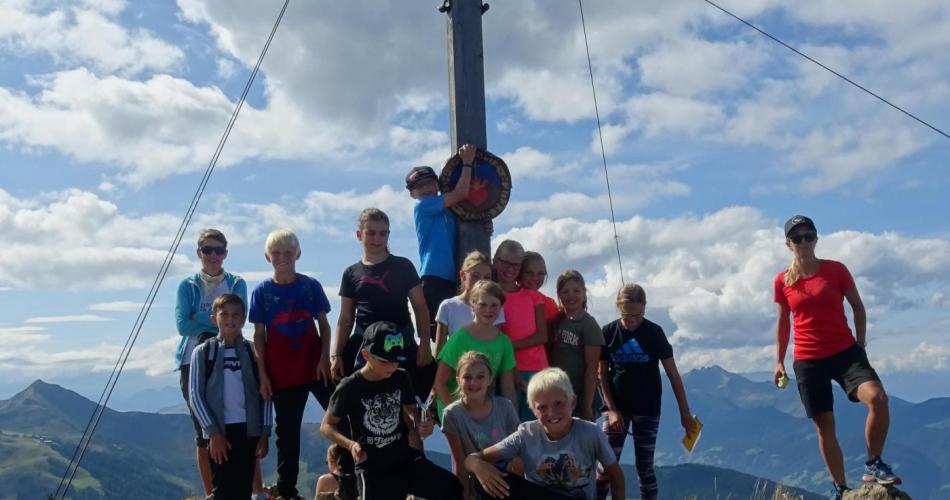 Kinder der 1b stehen auf dem Gratlspitz-Gipfel mit Kreuz im Hintergrund